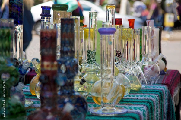 Fototapeta Close Up, Isolated View of Glass Bongs on Flea Market Table, Sunlit Out of Focus Background