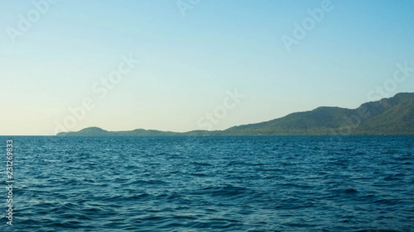 Fototapeta small island with deep blue dark sea view in distance clear sky