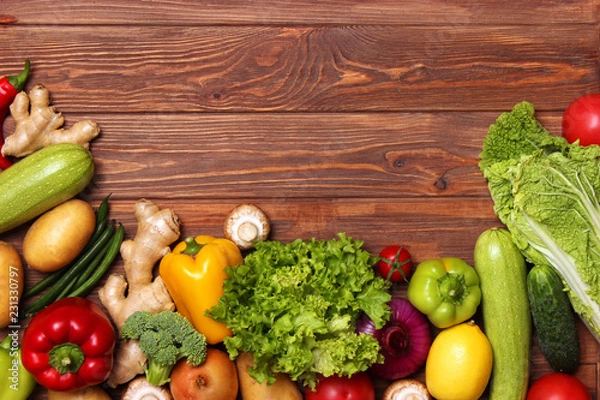 Fototapeta Different fresh vegetables on a wooden table top view. Proper and healthy food, diet, vegetarian. Cooking food, vegetable dishes. flat lay