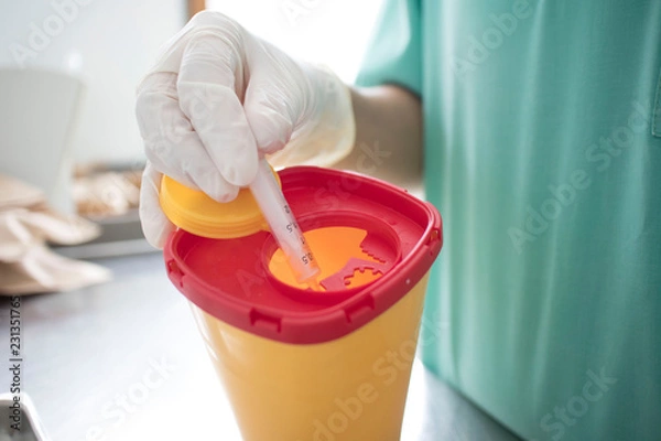 Fototapeta Doctor put syringe in red disposal boxes