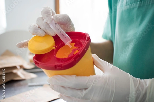 Fototapeta Doctor put syringe in red disposal boxes. concept of pandemic, coronavirus, virus, disinfection, panic.