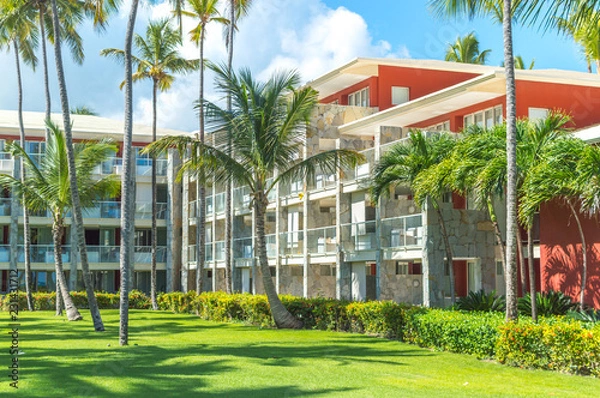 Fototapeta Buildings among palm trees in the resort of Punta Cana.
