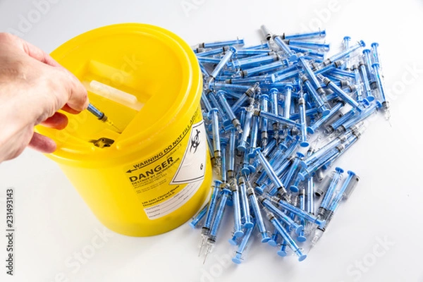 Fototapeta Needles being put ito a sharps bin