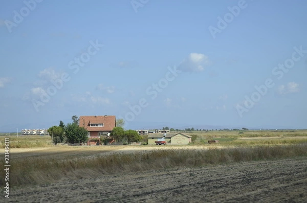 Fototapeta Farm house with the tractor in field