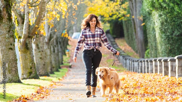 Obraz Kobieta spaceru golden retriever psa w jesienne liście