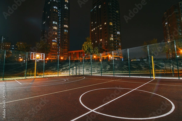 Obraz Illuminated basketball playground with red pavement, modern new basketball net and lens flares on background. 