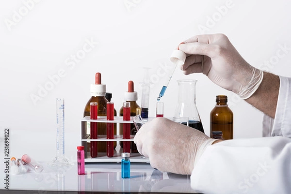 Fototapeta test tubes and laboratory tests with colored liquids, hand in glove holding test tube