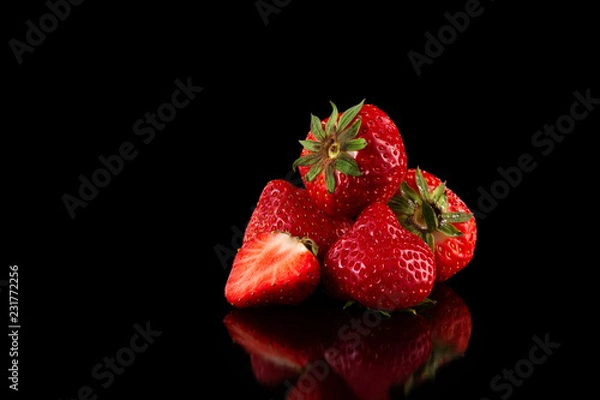 Fototapeta Macro image of fresh red strawberries group isolated at black background with reflection.