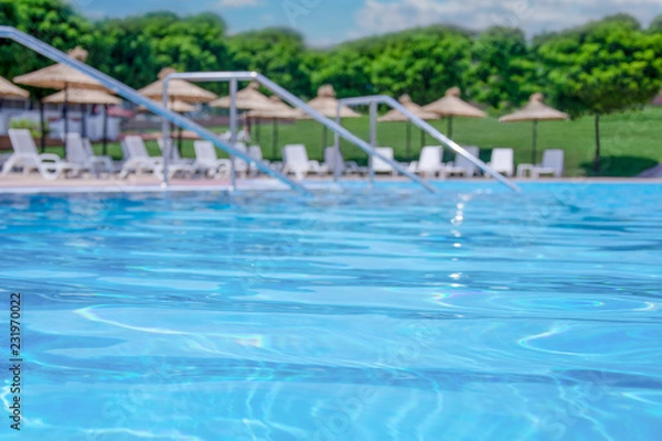 Fototapeta Swimming pool surface with blurred poolside in the background