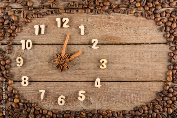 Obraz Ozdobny zegar z drewnianymi cyframi i strzałkami z lasek cynamonu, pokazujący 2 godziny, na drewnianym tle i ramce z ziaren kawy. Kuchnia, reklama, baner, miejsce na kopię, płasko.