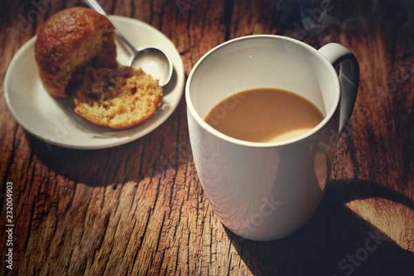 Fototapeta Hot coffee on wooden table, The best instant coffee served with banana cake. Porcelain coffee cup on table with dessert, Selective focus and free space for text. Industrial food and drink concept.