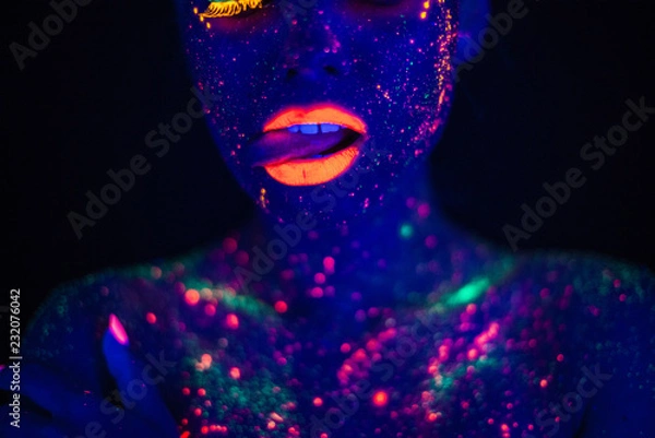Obraz Portret pięknej kobiety mody w Neonowym świetle UF. Modelka z fluorescencyjnym kreatywnym makijażem psychodelicznym, projekt artystyczny modelki tancerki dyskotekowej w UV, kolorowy abstrakcyjny makijaż