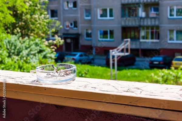 Obraz Glass ashtray with cigarette butts on the balcony railing