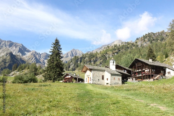 Fototapeta The Walser town of Follu, with wood and stone lodges, high mountains, forests and pastures, in summer, in Val d'Otro valley, Alps mountains, Italy