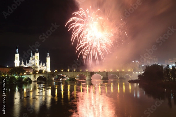 Fototapeta The fireworks during the 2018 Pilar festival next to the Pilar Cathedral and the Stone Bridge over the Ebro river, in Zaragoza, Aragon region, Spain