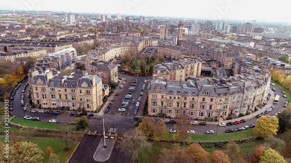 Fototapeta Low level aerial image over the autumn foliage of trees in Kelvingrove Park, Glasgow, to the elegant buildings of Park Circus.
