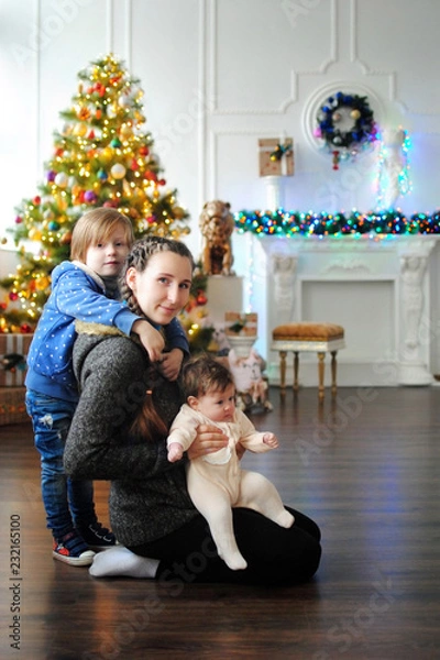 Obraz Дети с мамой ждут чудо в Новый год. С новым годом! Счастливого Рождества! Новогодняя елка с рождественскими игрушками. Брат с сестрой и мамой празднуют.
