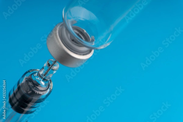 Fototapeta Medical syringe and vial on blue background with selective focus and crop fragment
