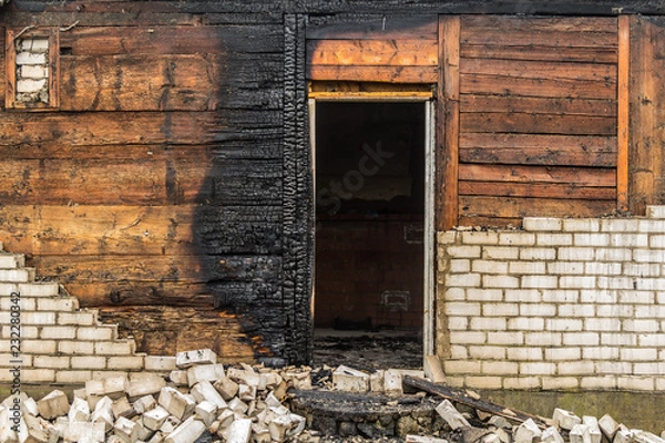 Fototapeta charred wooden parts of a burnt house in countryside