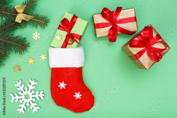 Fototapeta Santa's boot, gift boxes and fir tree branch on green background