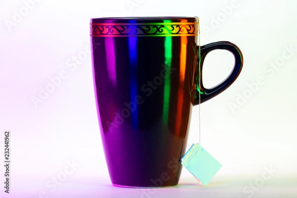 Fototapeta Cup of tea with tea bag from side with colorful lighting