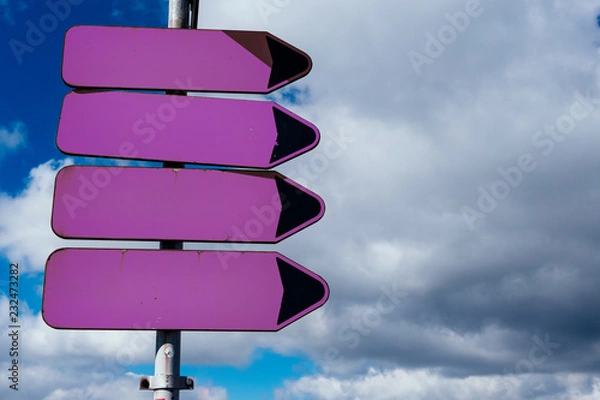 Fototapeta Empty purple road sign pointers without inscriptions against blue sky with clouds. Space, place for text.