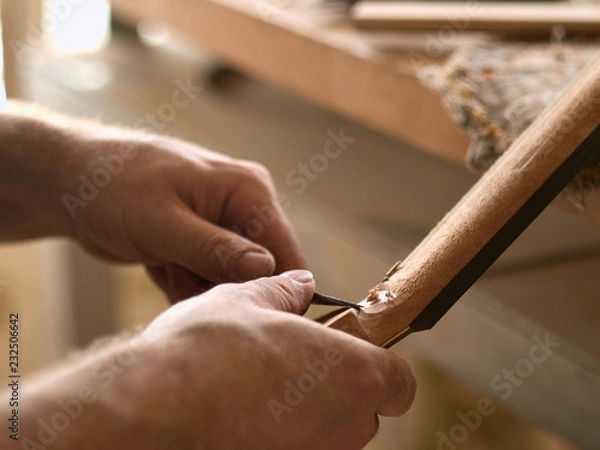 Fototapeta luthier is working on the neck of a classical guitar.