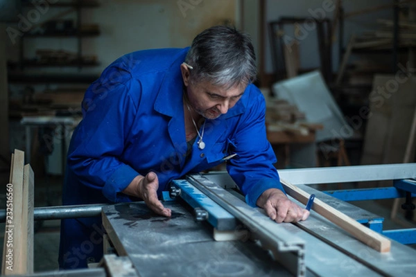Fototapeta Carpenter at work at his workshop, wood processing on a woodworking machine