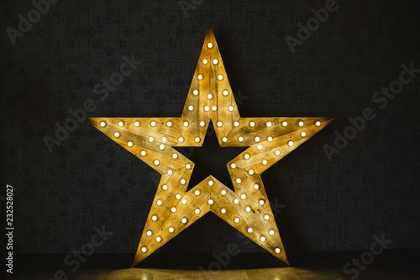 Obraz The wooden star with light. Under a black background.