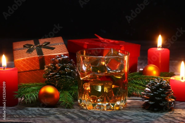 Obraz Glass with cognac or whiskey, Christmas balls and candles. New Year's tree, balls and glass with alcohol.