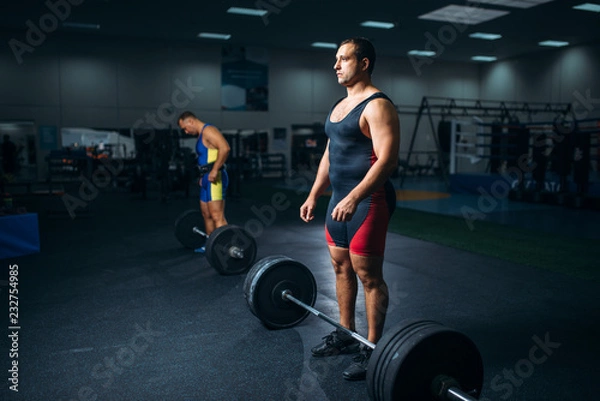 Fototapeta Two weightlifters doing exercise with barbells