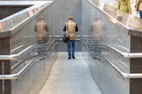 Fototapeta Entrance to the underground passage with shiny railing and double reflection of a man