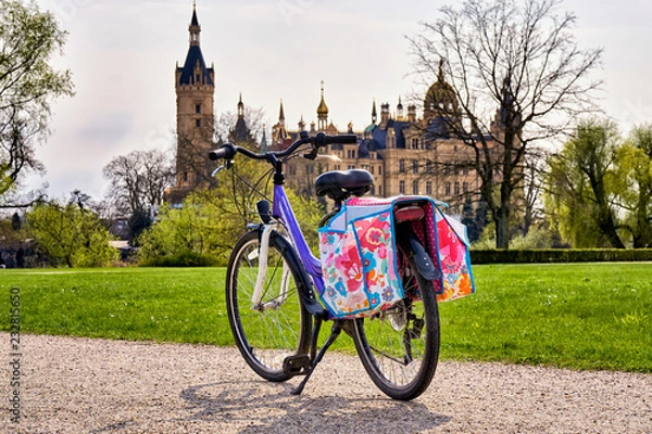 Fototapeta Children's bicycle with saddlebags in the park, with Schwerin Castle in the background.