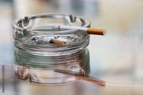 Fototapeta ashtray with cigarette on a reflecting surface of a glass table