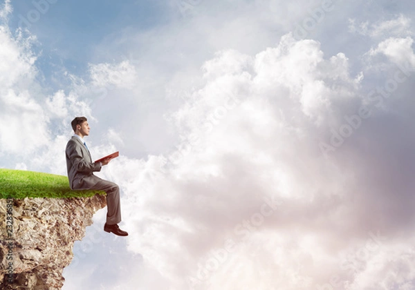 Fototapeta Student guy in suit with book in hands preparing for exam