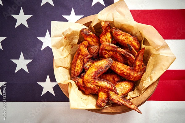 Fototapeta top view of delicious fried chicken wings in a bowl with sauces on the background of the USA flag