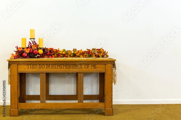 Fototapeta Communion table decorated for the fall with candles and colored leaves on a isolated background.