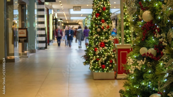 Fototapeta christmas tree in focus right side of frame, people blurred in left side of frame