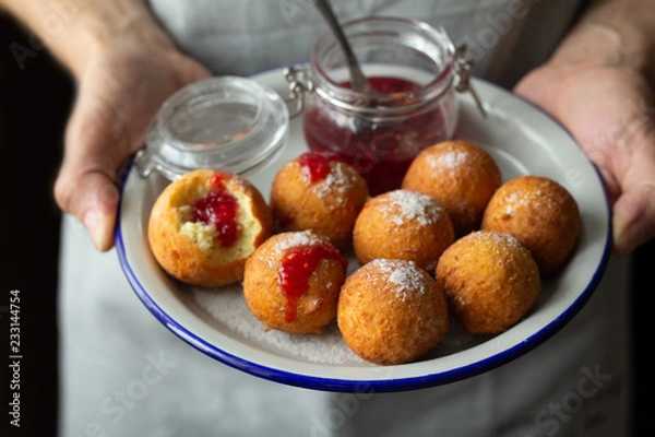 Obraz donuts with raspberry jam in male hands.
