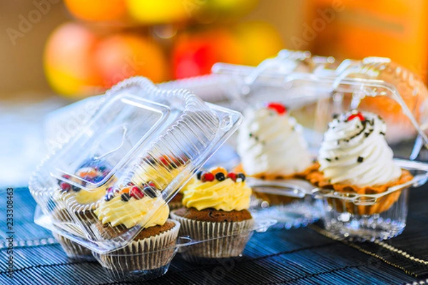 Obraz Cakes in a plastic disposable container on a colored background