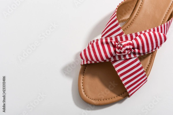 Fototapeta Sandalia de mujer con lineas rojas y blancas con un moño. Moda. En fondo blanco
