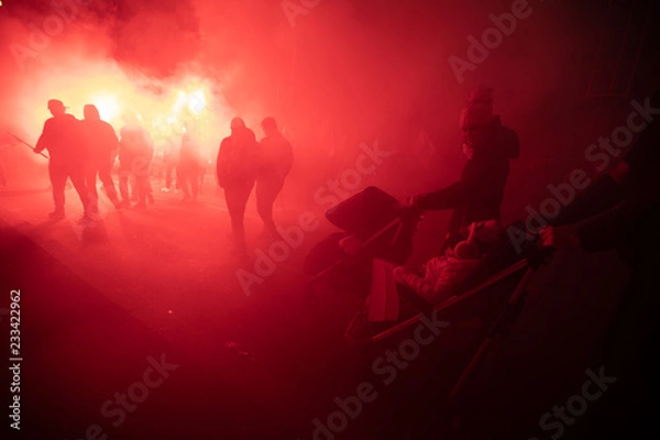 Obraz People carry Polish flags and burn flares as they walk across the Poniatowski Bridge during a march marking the 100th anniversary of Polish independence in Warsaw, Poland November 11, 2018. 