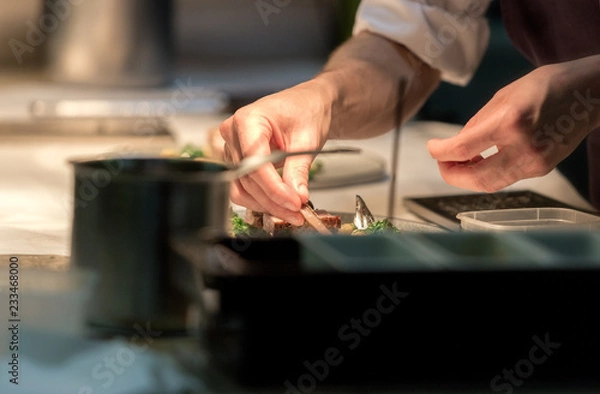 Fototapeta Restaurant chef preparing a plate under a warm light