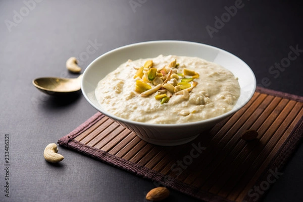 Fototapeta Sweet Rabdi or Lachha Rabri or basundi, made with pure milk garnished with dry fruits. Served in a bowl over moody background. Selective focus