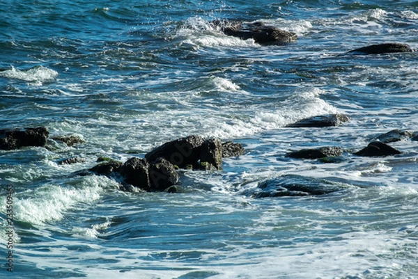 Fototapeta Photo of the sea on which the waves with white crests break on the stones