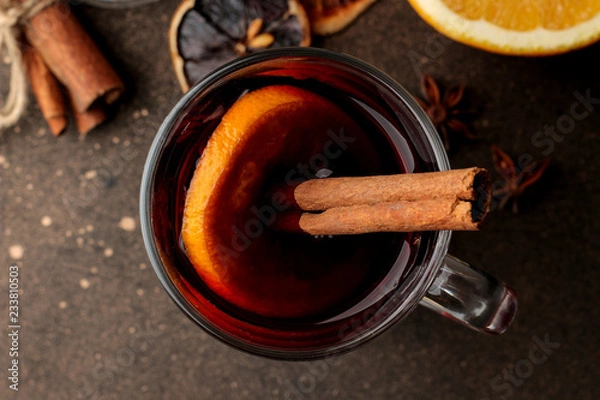 Fototapeta Hot mulled wine with cinnamon and orange in glass cups close-up on a dark background. View from above. Christmas. new Year.
