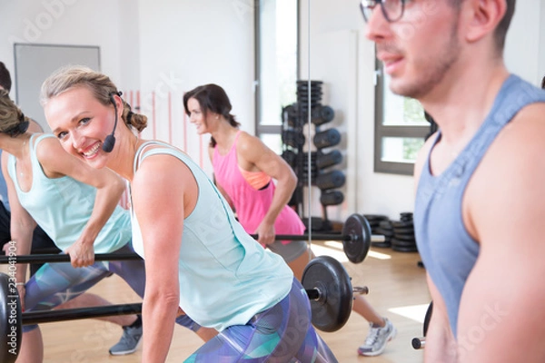 Obraz young sports group is training aerobics pump with barbell in the gym