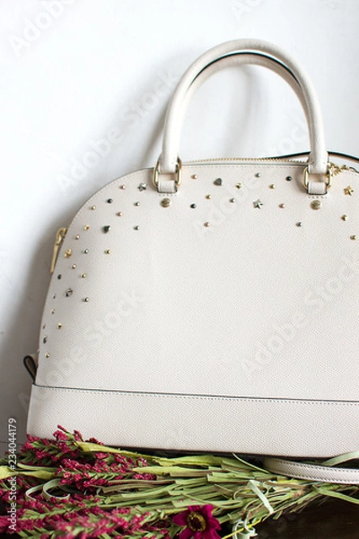 Obraz womens leather bag on a red leather sofa, leather white handbag (vertically, close up)