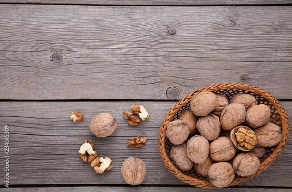 Fototapeta Walnuts kernels in basket on grey wooden background