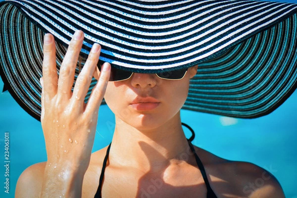 Obraz Portrait of a girl in glasses and a hat on a tropical beach